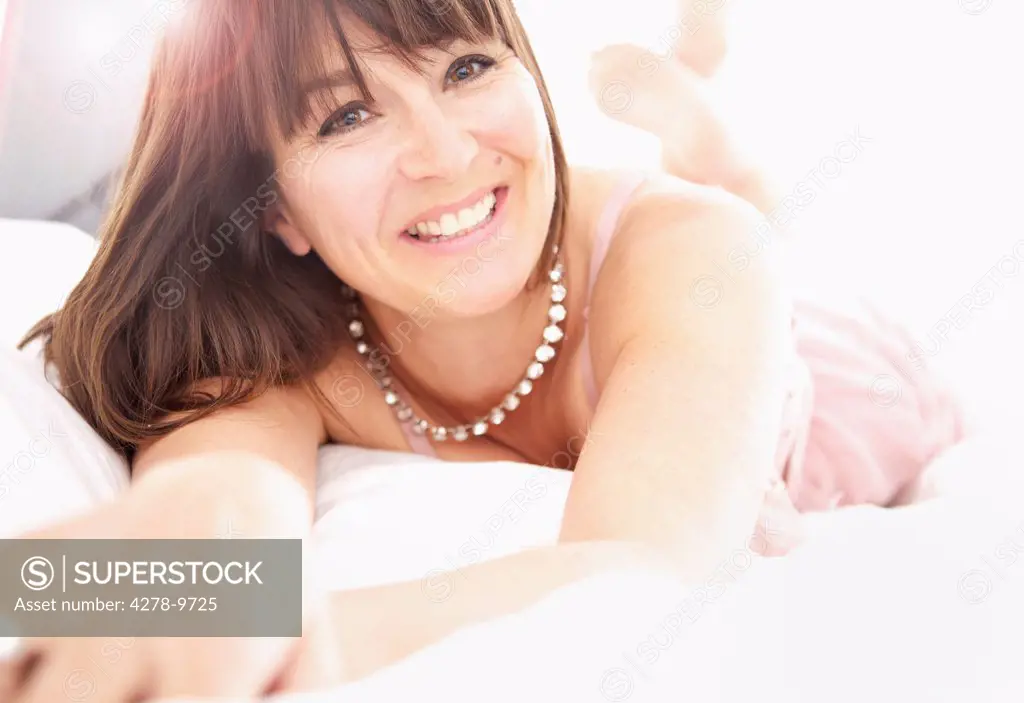 Smiling Woman Lying on Bed, Close-up View