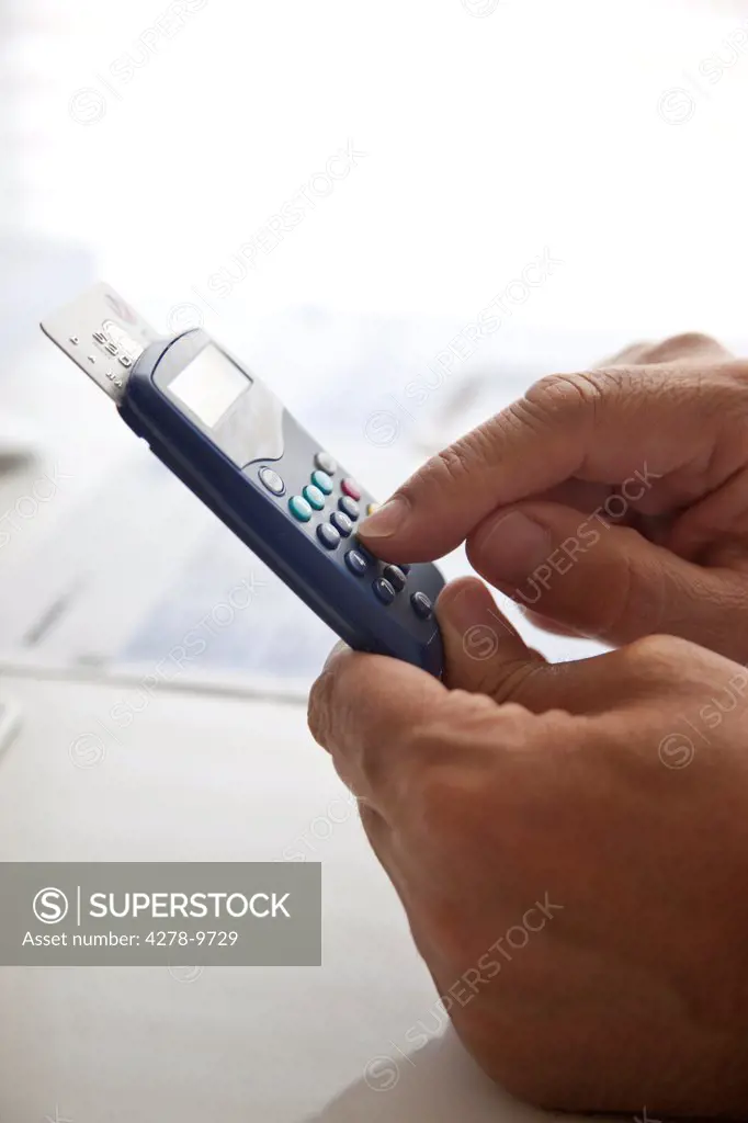 Man's Hands Typing into a Banking Card Reader
