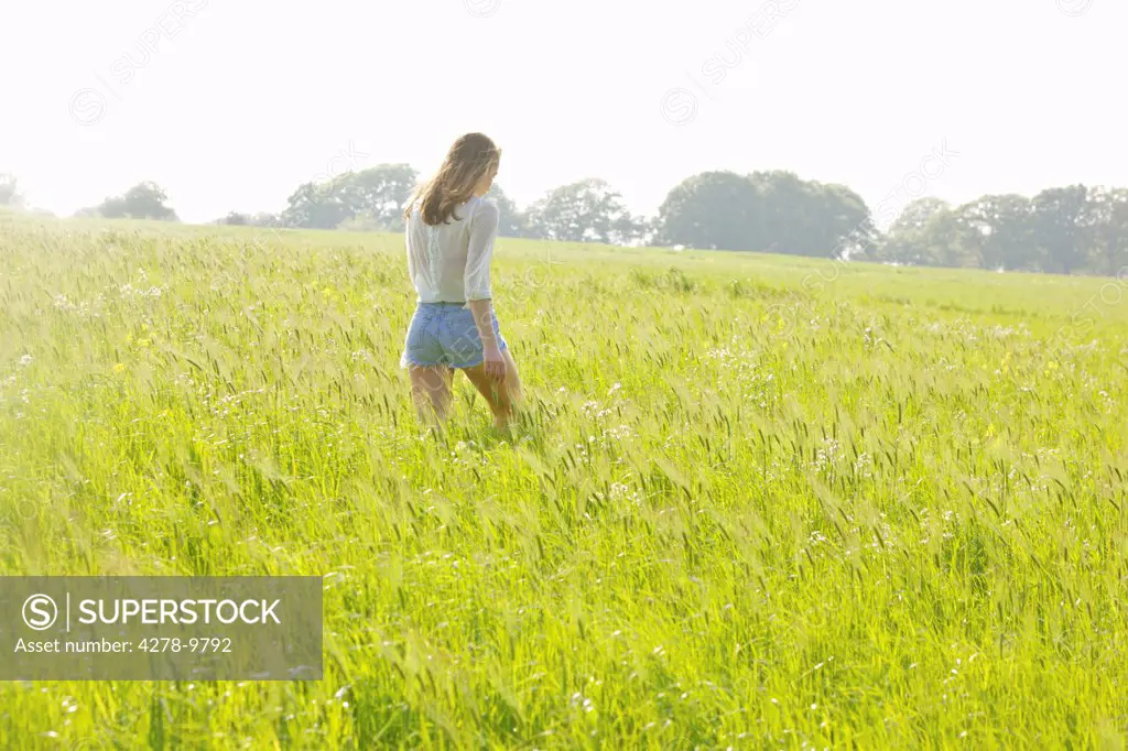 Back View of Young Woman Walking in a Field