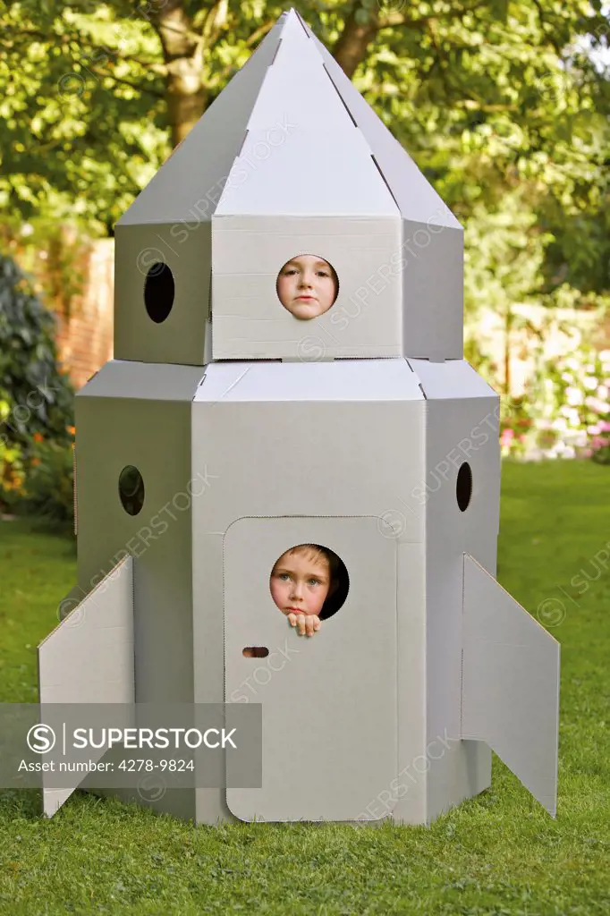 Two Boys Looking Out from Window of Cardboard Rocket Spacecraft
