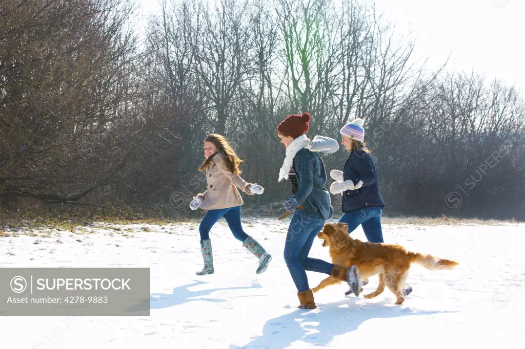 Teenage Girls and Dog Running in Snow