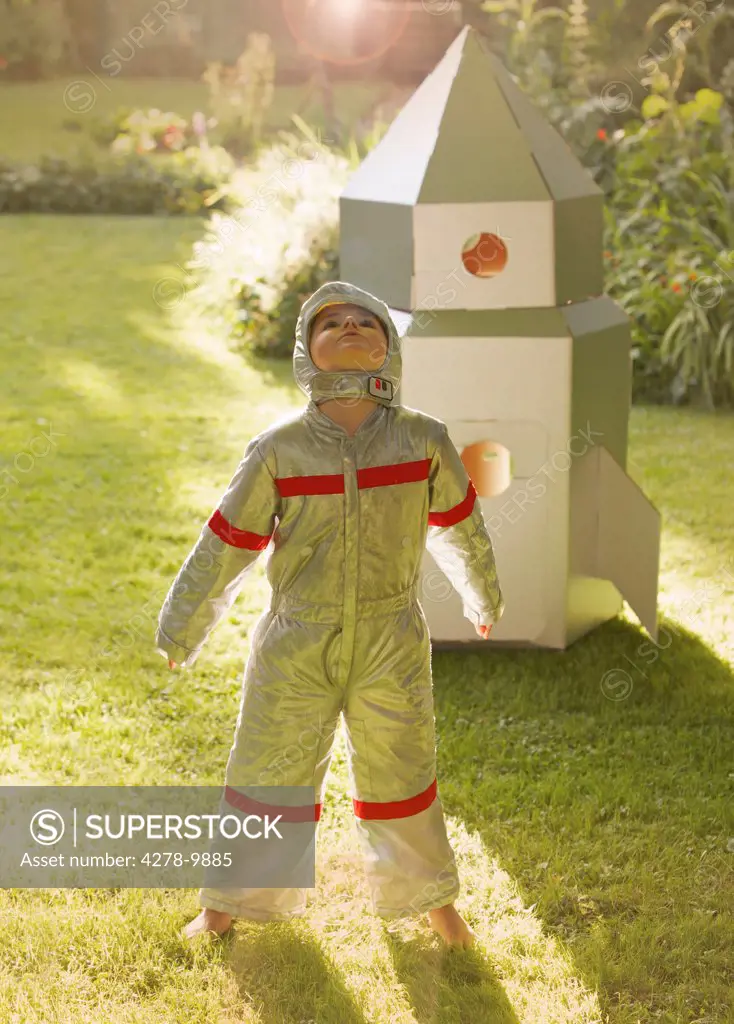Boy Wearing Space Suit Standing in front of Cardboard Rocket Spacecraft