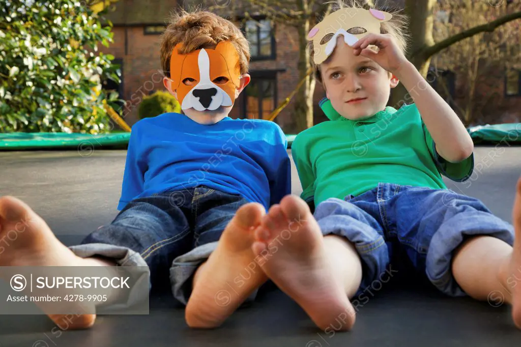 Two Boys Wearing Masks Lying on Trampoline
