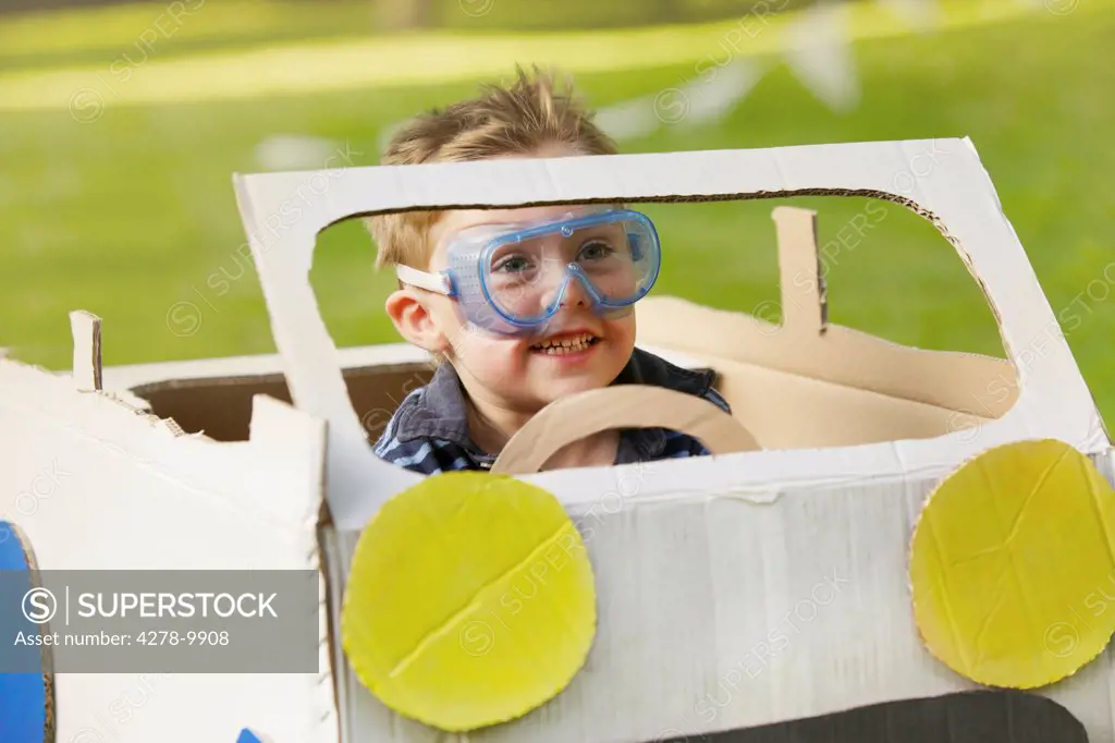 Boy Wearing Goggles Driving Cardboard Car