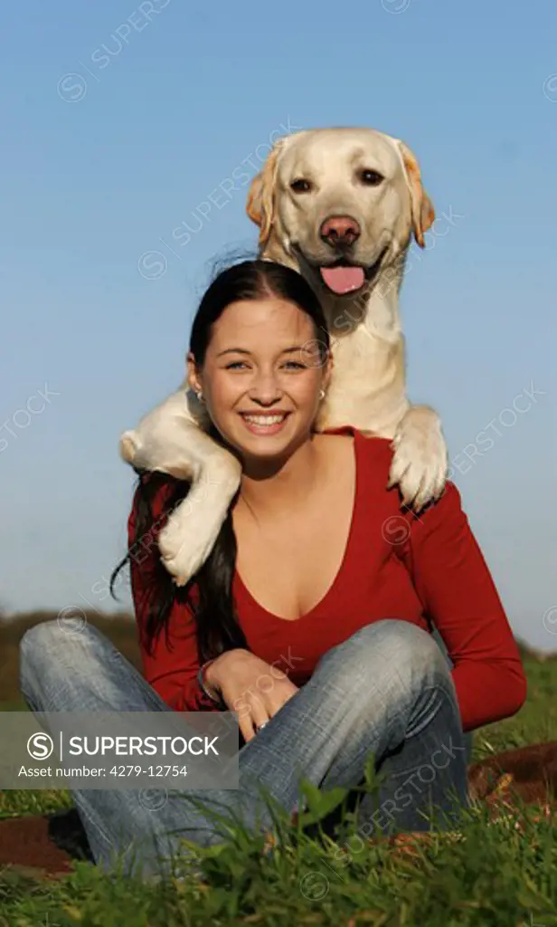 young woman sitting - Labrador Retriever having paws on her shoulders