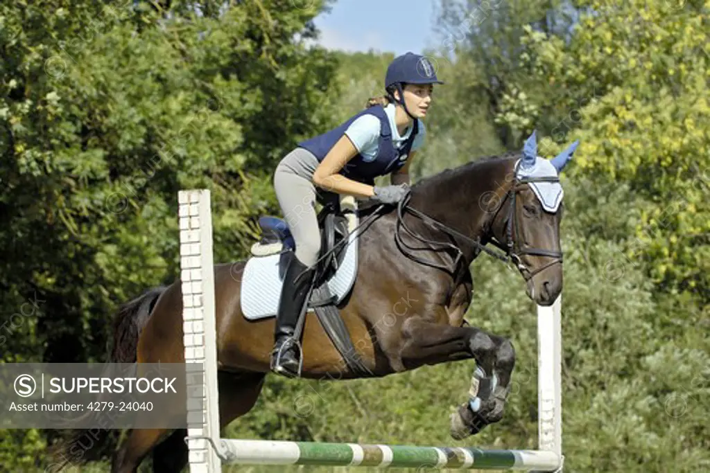 Young lady wearing a body protector and a riding hat while jumping