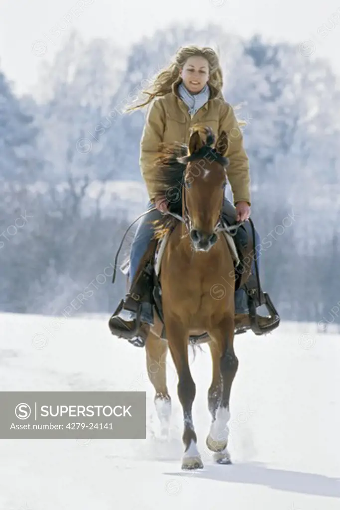 Young lady riding western-style on back of an Arabian horse at winter