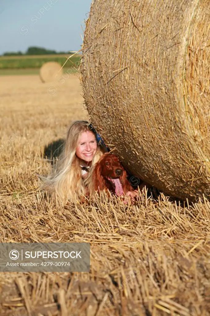 woman with Irish Red Setter - lying behind bale of straw