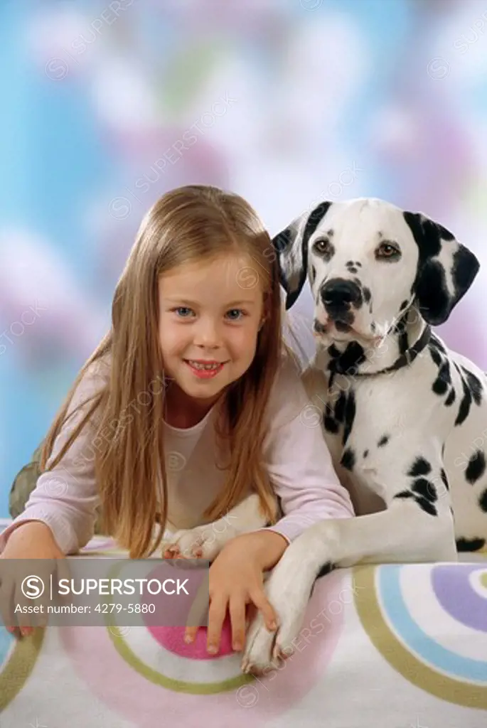 girl lying beside a dalmatian dog