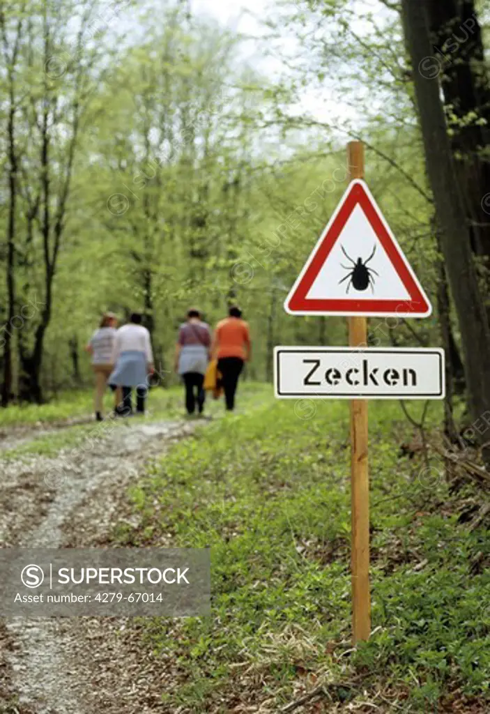 DEU, 2005: Hikers next to warning sign: ""Attention of ticks"".