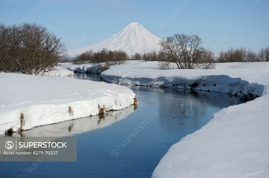 Tikhaya River flows through the snowy tundra. Kronotsky Volcano is in the background. Kamtchatka, Russia