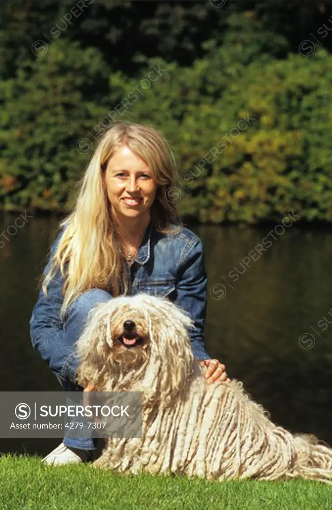 puli dog lying on meadow beside a woman