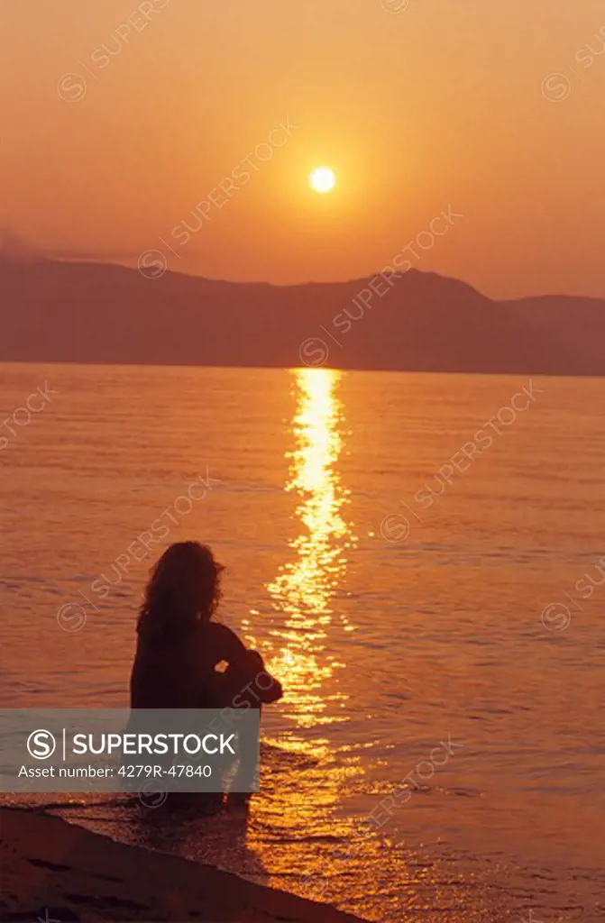 woman - sitting in water - sunset