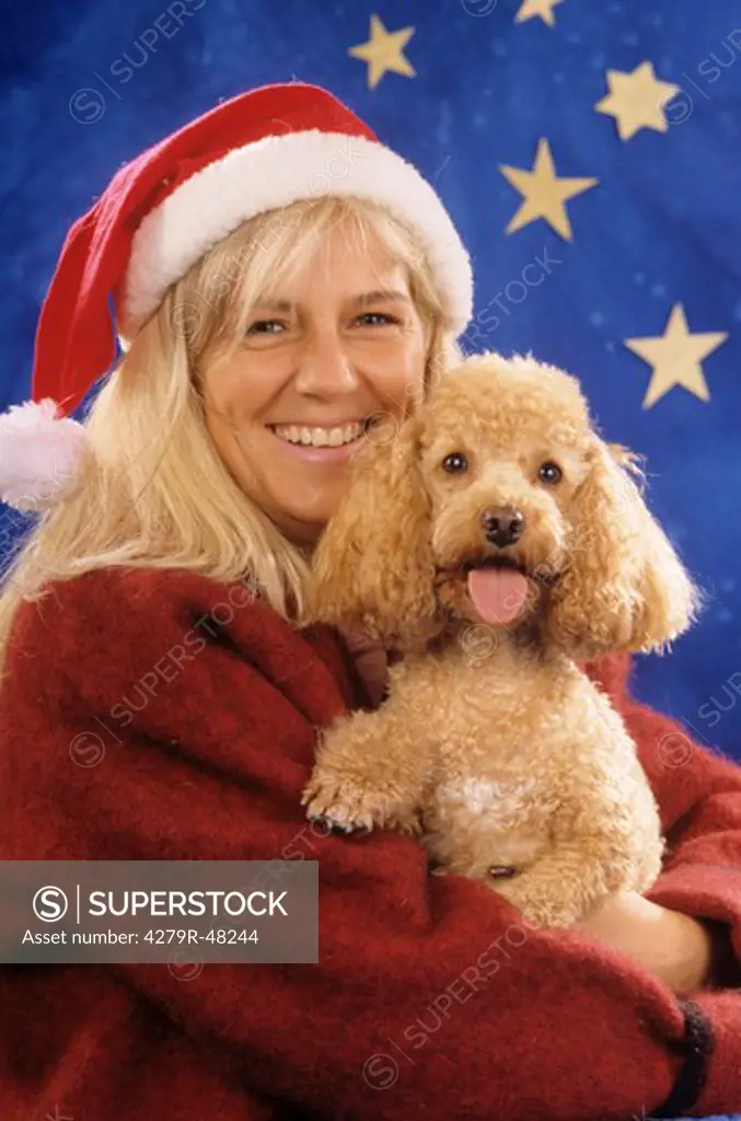 woman with poodle in front of christmas decoration