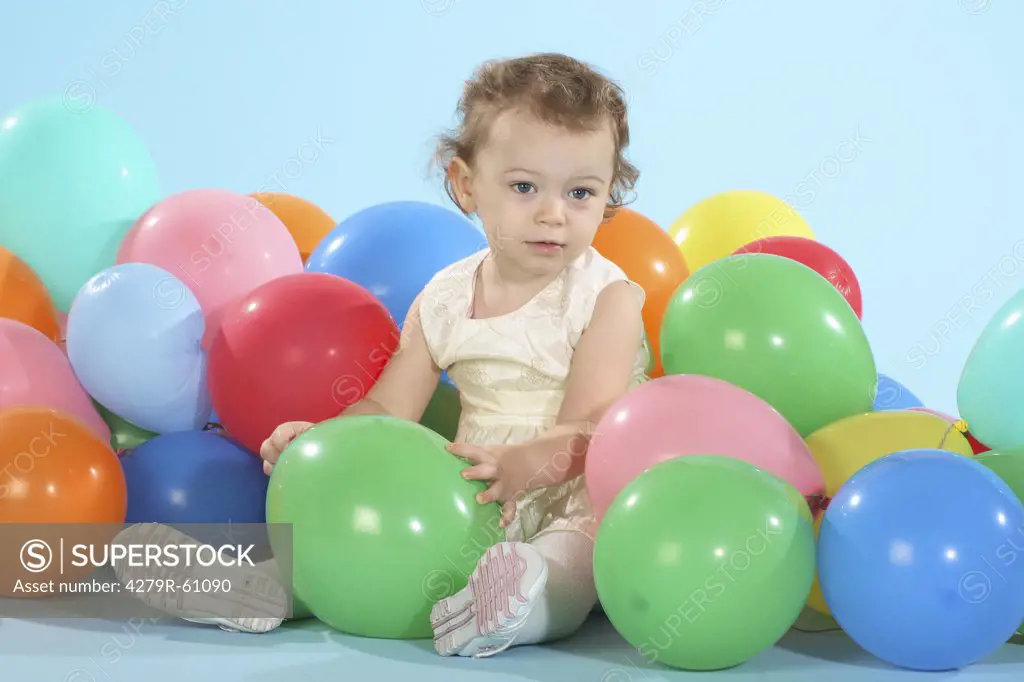 little girl sitting in between balloons
