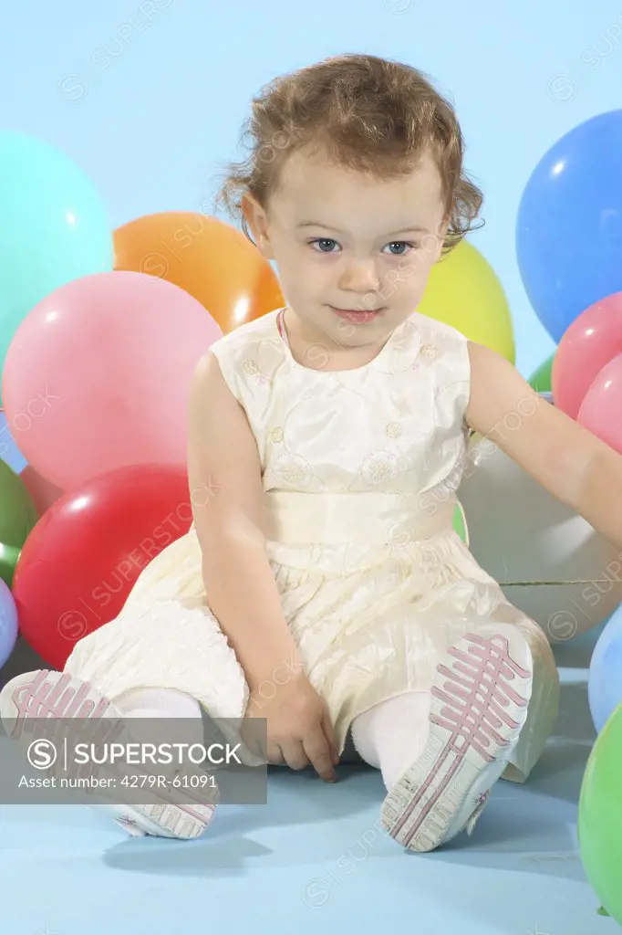little girl sitting in front of balloons