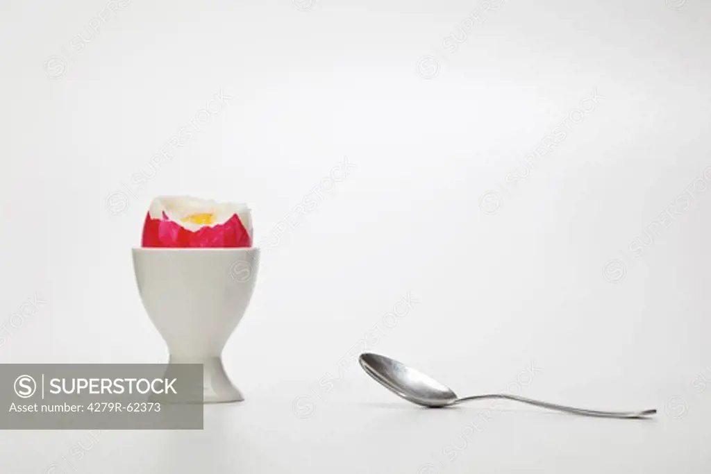 half of an Easter egg in an egg cup with a spoon