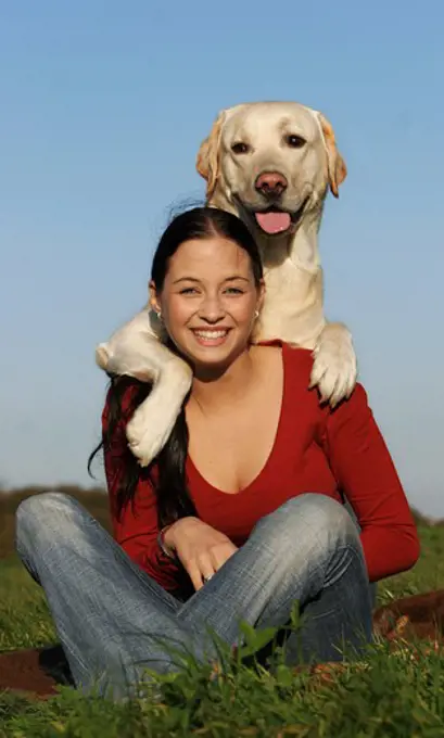 young woman sitting - Labrador Retriever having paws on her shoulders
