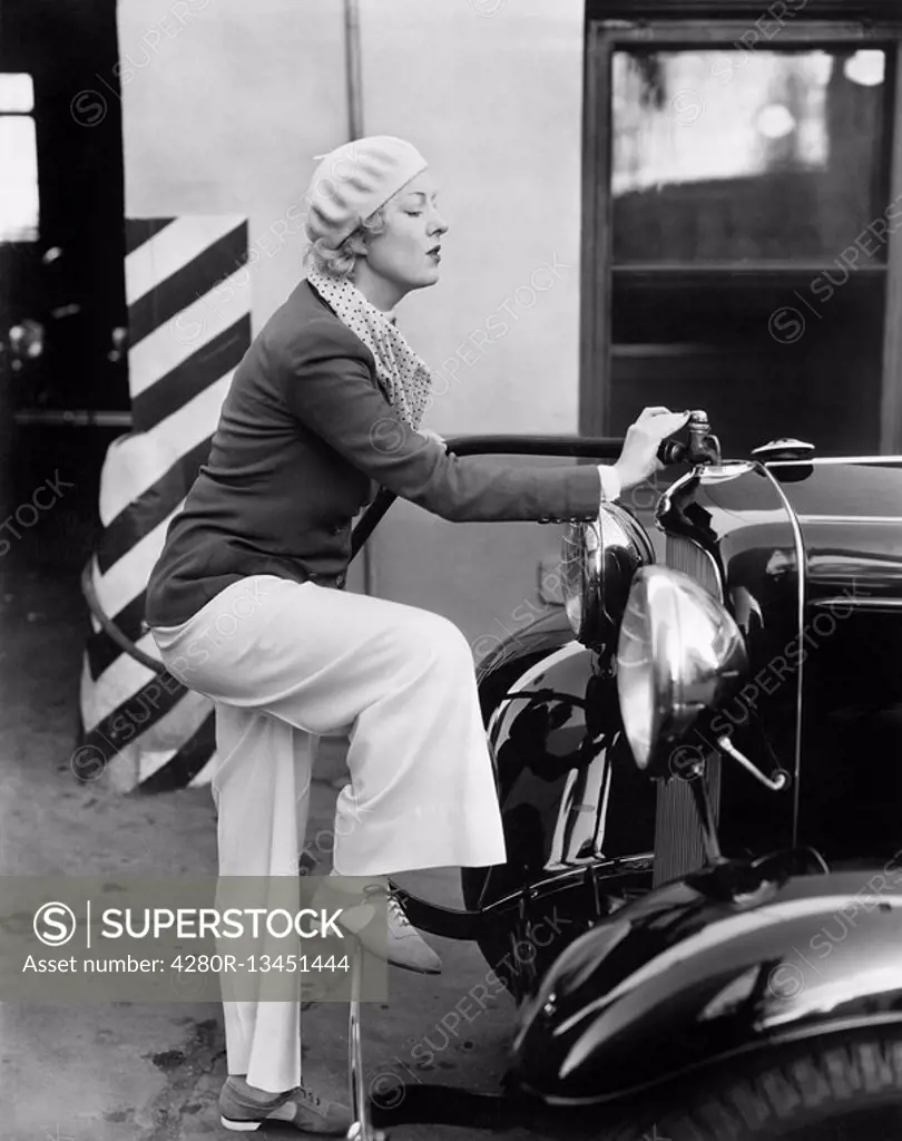 Woman putting gas in the front of her car All persons depicted are not longer living and no estate exists Supplier warranties that there will be no mo...