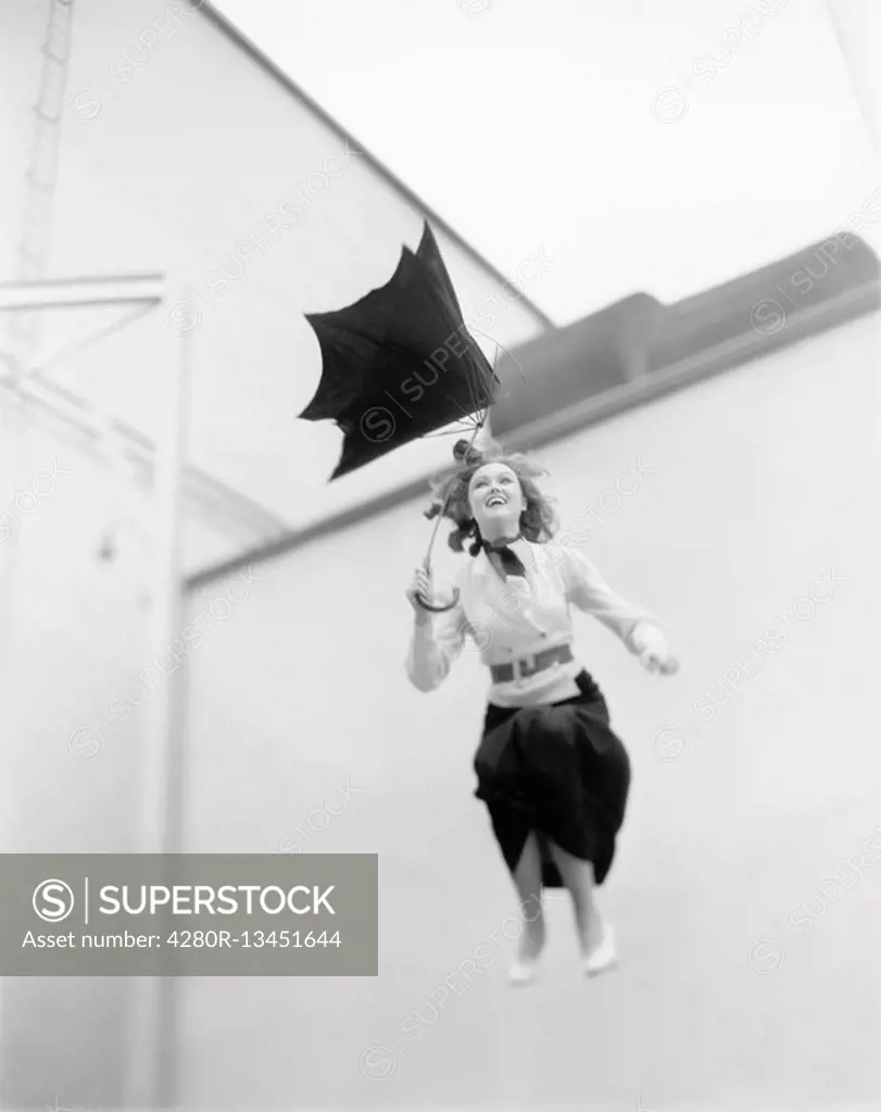 Young woman is blown away, jumping from a roof with an umbrella All persons depicted are not longer living and no estate exists Supplier warranties th...