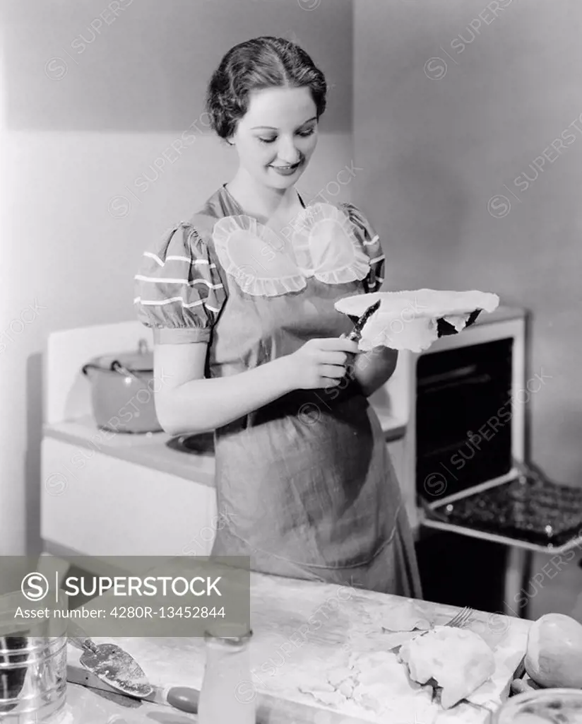 Woman preparing a pie in the kitchen All persons depicted are not longer living and no estate exists Supplier warranties that there will be no model r...