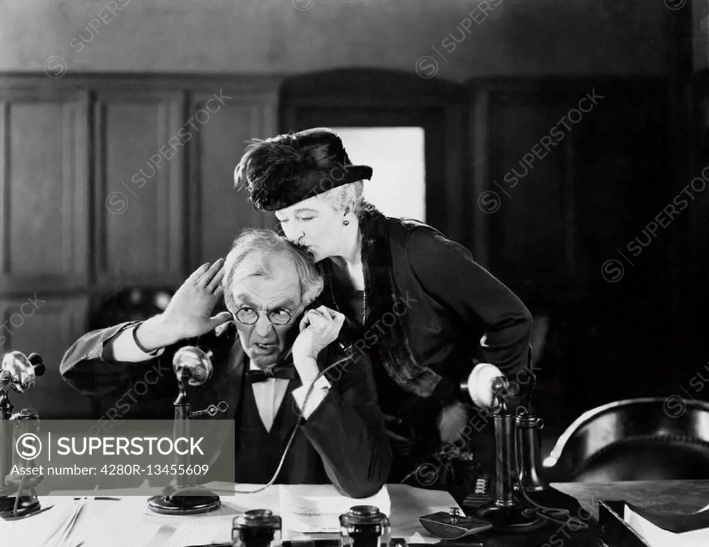 Man on a phone being kissed by a woman on his head All persons depicted are not longer living and no estate exists Supplier warranties that there will...