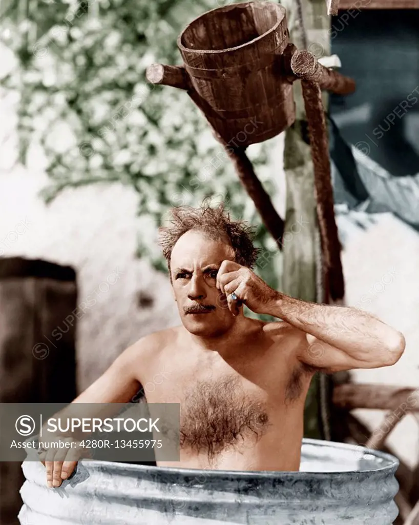 Man sitting in a barrel taking a bath and looking through his monocle Old Visuals