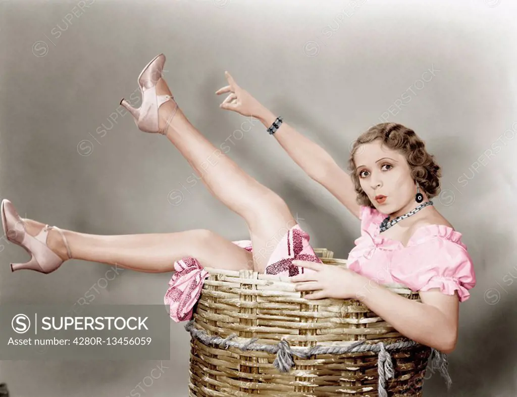 Young woman sitting in a basket looking surprised Old Visuals