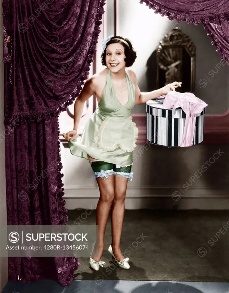 Woman walking into a room wearing lingerie and holding a hat box Old Visuals