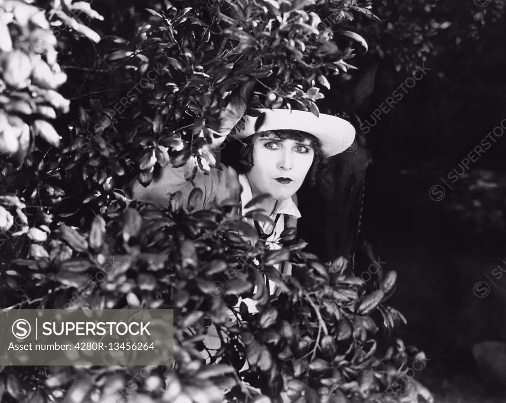 Woman peeking through bushes