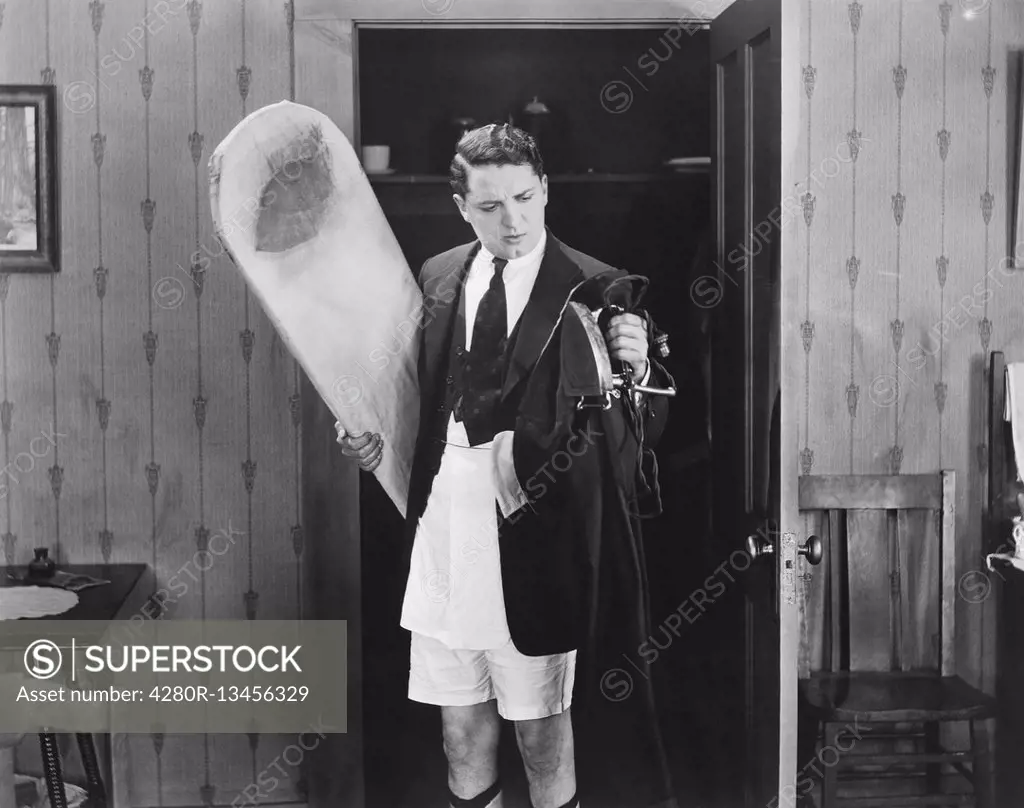 Man in boxer shorts holding iron and ironing board