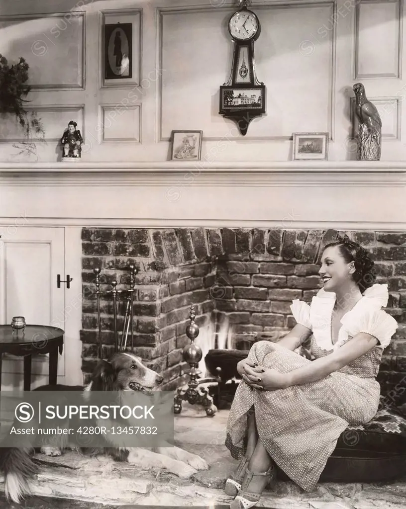 Relaxing in front of the fireplace with her collie (OLVI007_OU827_F)