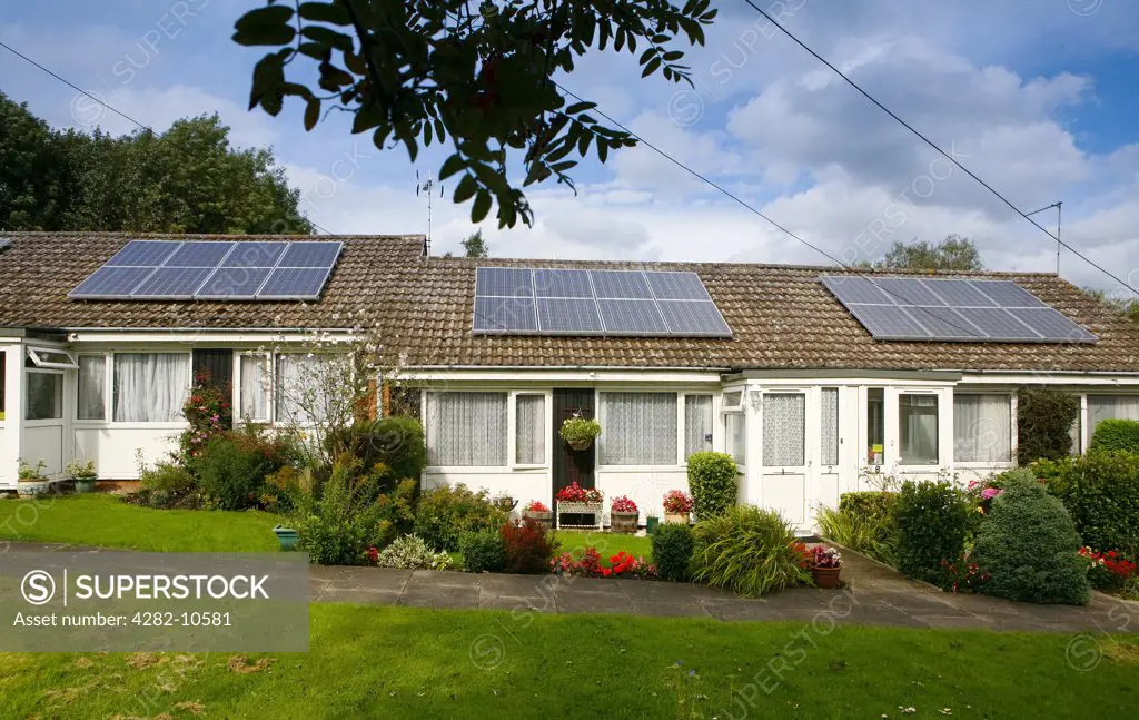 England, Warwickshire, Warwick. A row of bungalows with solar panels fitted to their roofs. Solar panels make use of renewable energy from the sun, and are a clean and environmentally sound means of collecting solar energy.
