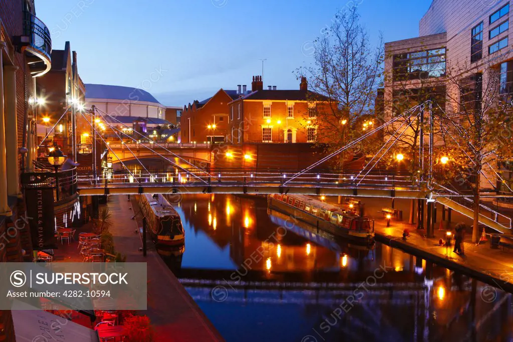 England, West Midlands, Birmingham. Narrowboats on the canal in Brindleyplace at dusk. Brindleyplace is an award winning business and leisure destination in the heart of Birmingham city centre.