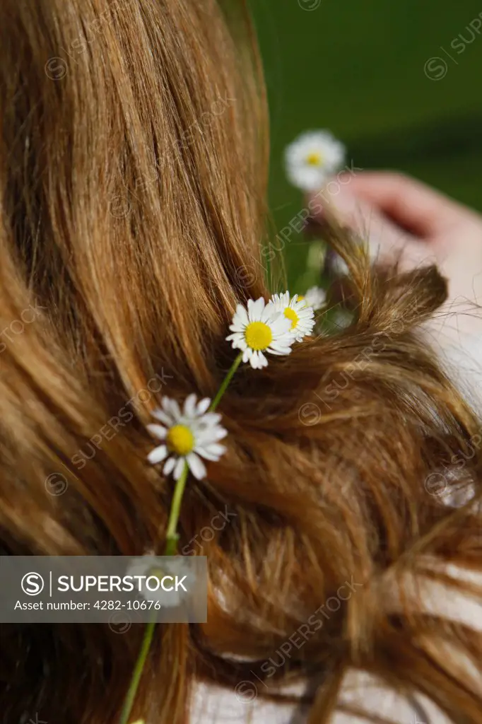 England, West Midlands, Birmingham. A woman holding up a daisy from the daisy chain she is wearing around her neck.