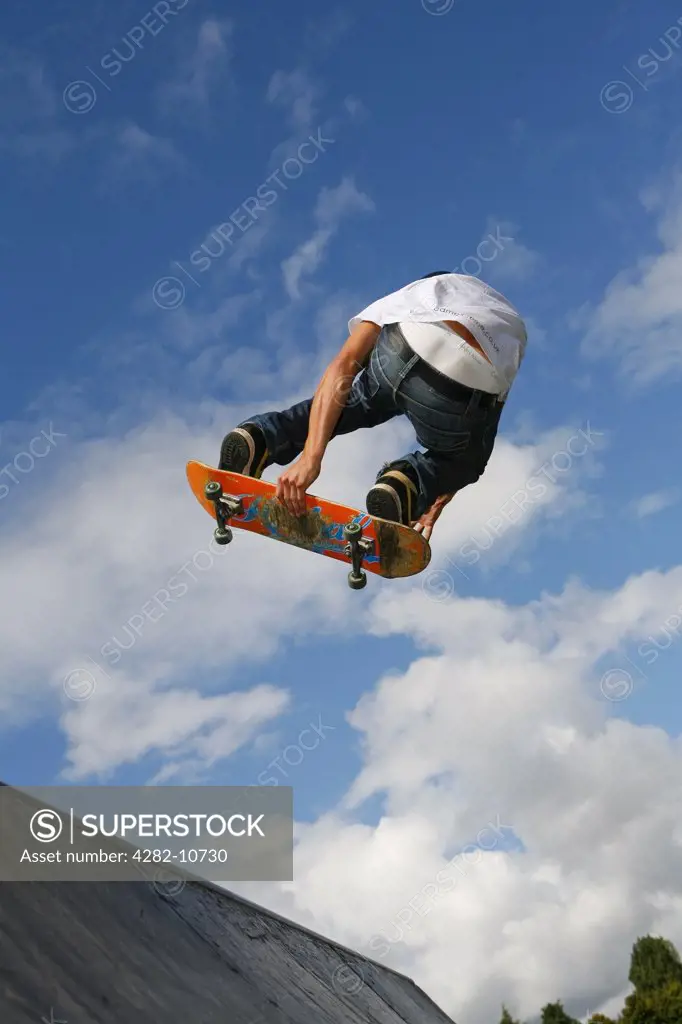 England, West Midlands, Birmingham. A skateboarder in mid-air above a ramp in a skateboard park in Birmingham.