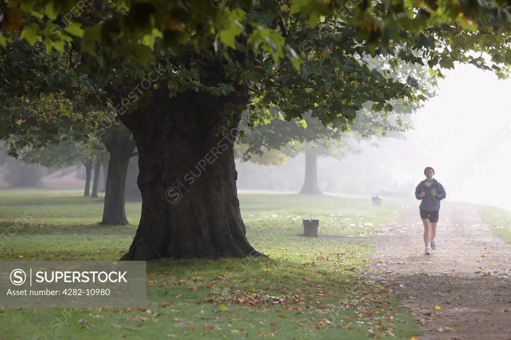 England, Oxfordshire, Oxford. Jogger by the River Thames on a misty morning.
