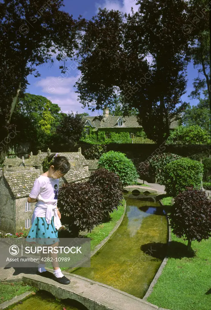England, Gloucestershire, Bourton-on-the-Water. Child walking through a model village.