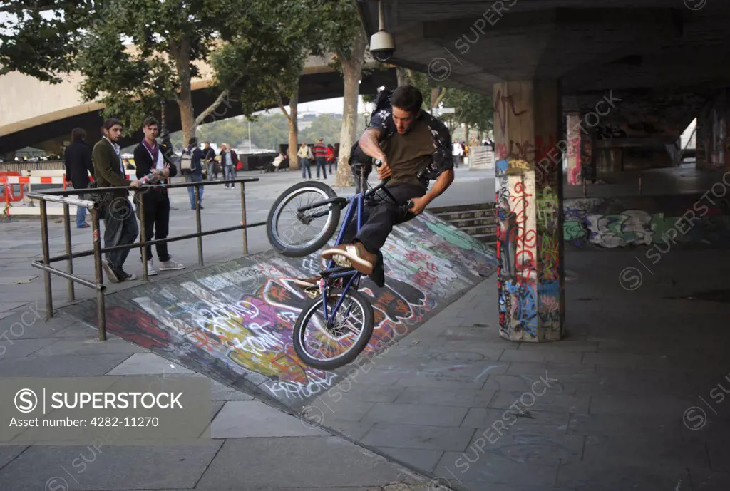 England, London, South Bank. A trick cyclist performing stunts on the South Bank.