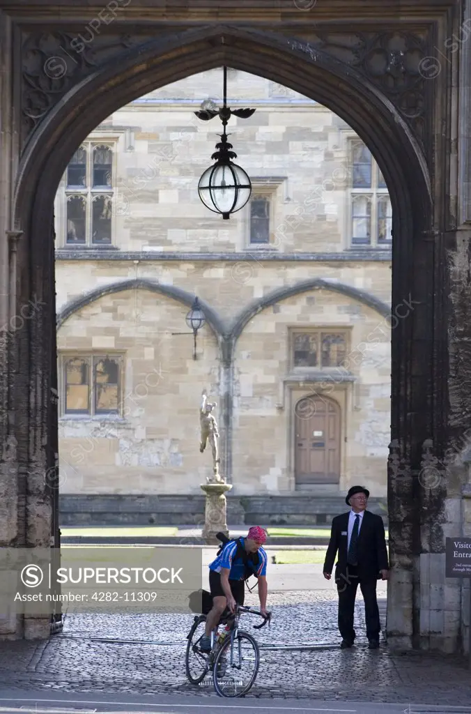 England, Oxfordshire, Oxford. Bursar and cyclist at the gate of Christ Church College.