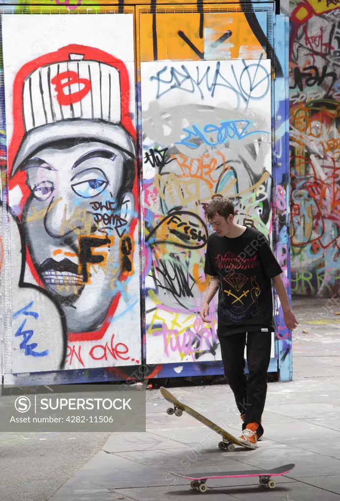 England, London, South Bank. A skateboarder against a backdrop of graffiti on the South Bank in London.