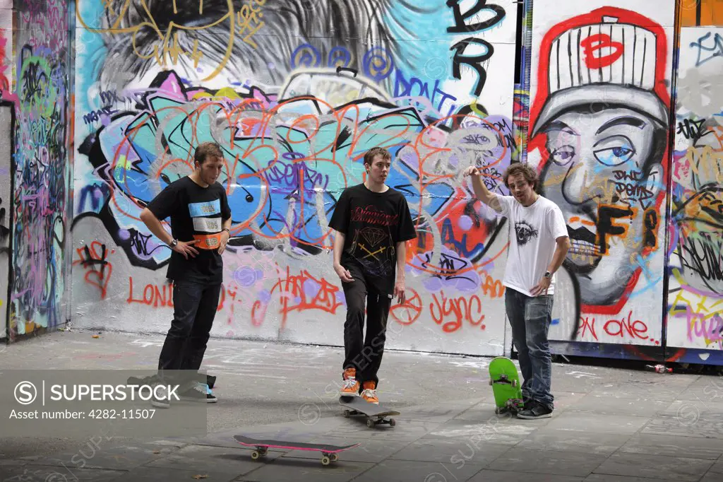 England, London, South Bank. Skateboarders against a backdrop of graffiti on the South Bank in London.