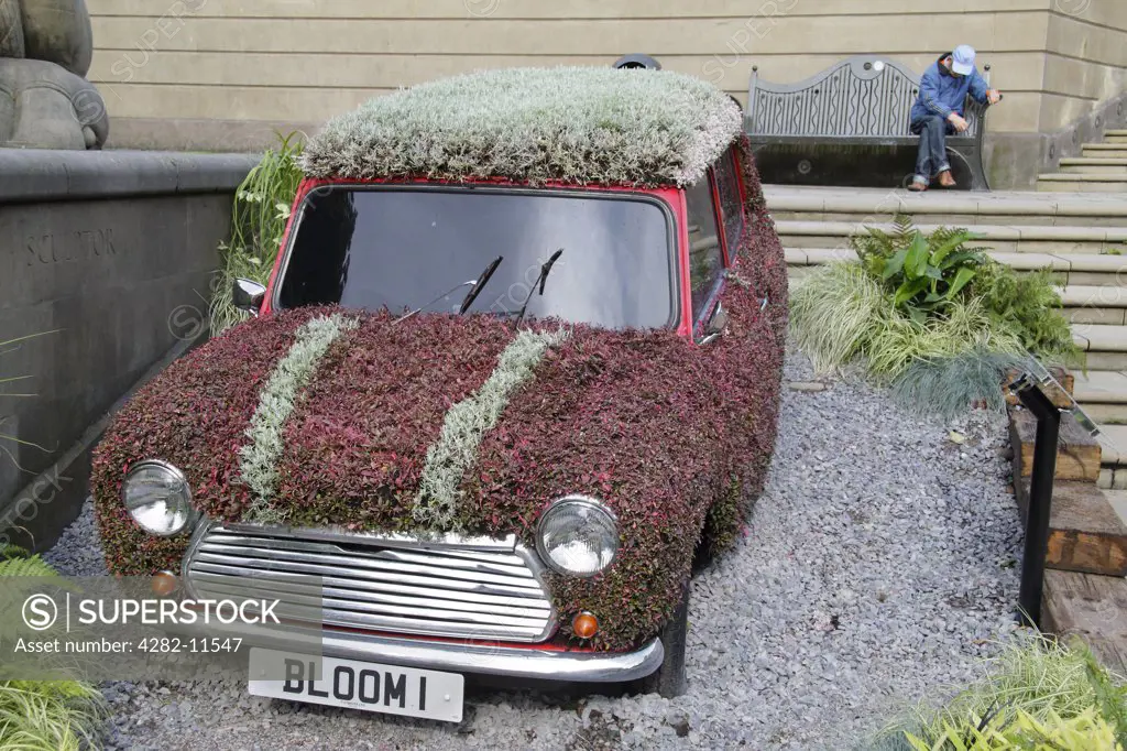 England, West Midlands, Birmingham. A classic mini adorned with flowers in Victoria Square, Birmingham as part of Birmingham's entry into the national finals of the RHS Britain in Bloom competition.