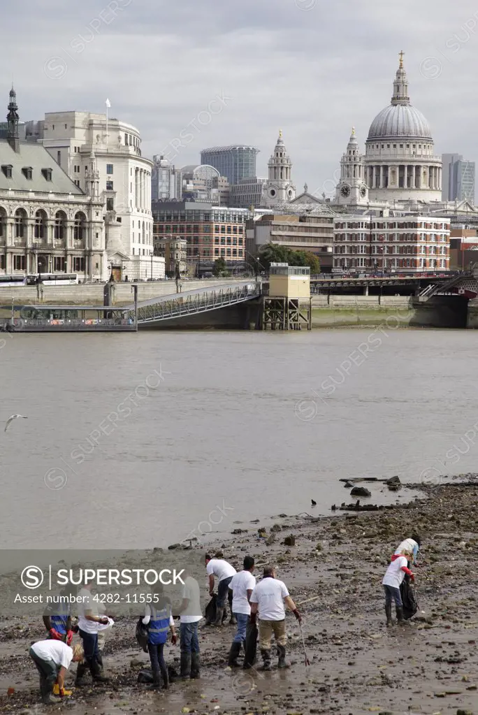 England, London, South Bank. Volunteers cleaning litter from the Thames shore line on the South Bank at low tide.