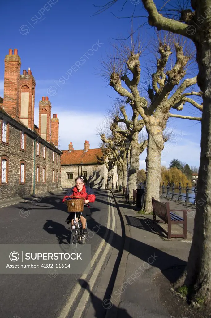 England, Oxfordshire, Abingdon. A woman cycling on her shopping bike at St Helen's Wharf in Abingdon.