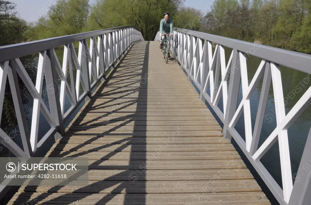 England, Oxfordshire, Kidlington. A man cycling on a footbridge over the River Thames at Kidlington.