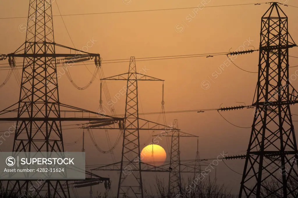 England, Oxfordshire, Radley. Electricity pylons silhouetted at sunset.