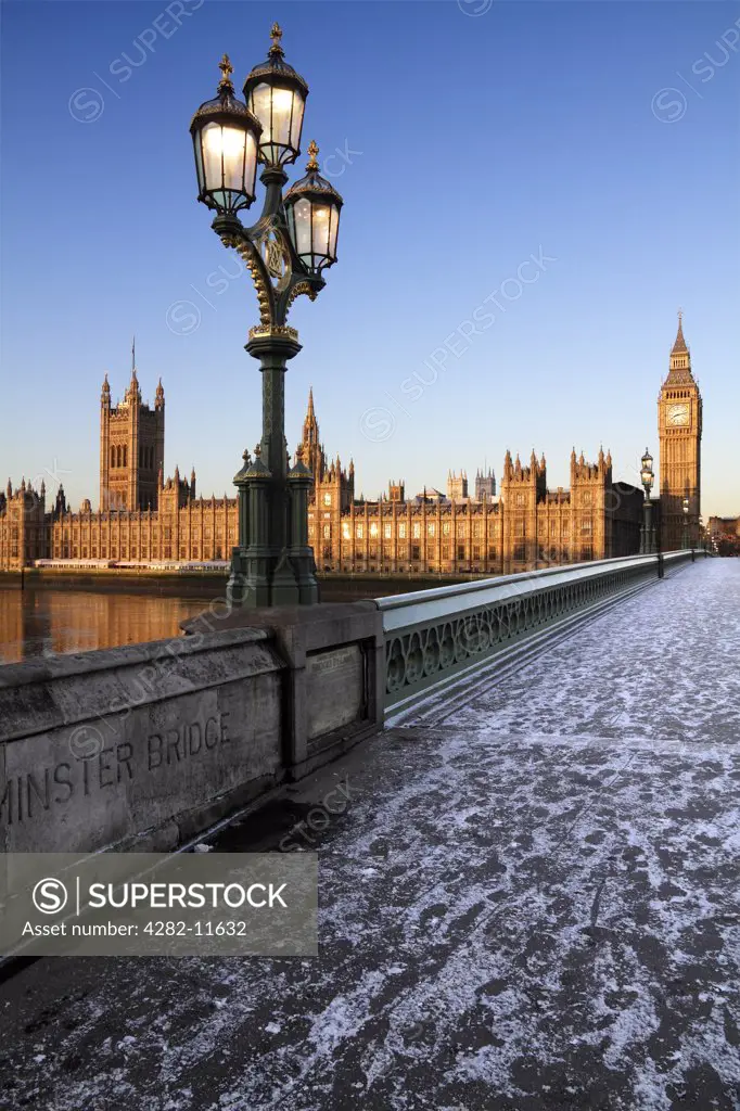 England, London, Westminster. An icy pavement over Westminster Bridge looking towards Big Ben and the Houses of Parliament at sunrise in winter.