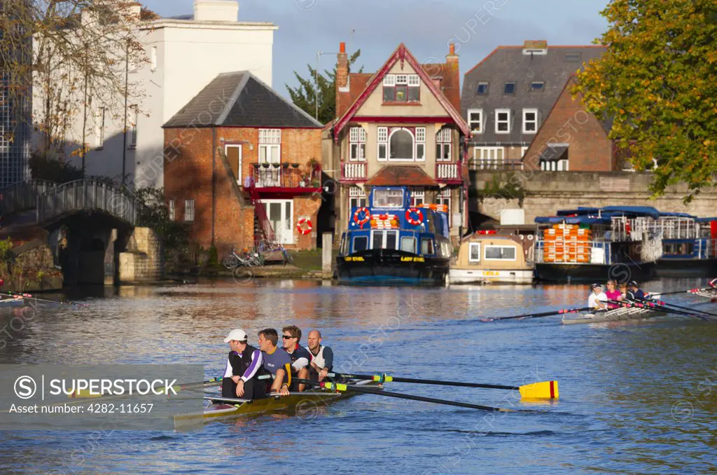 England, Oxfordshire, Oxford. Coxless fours rowing on the River Thames in autumn.