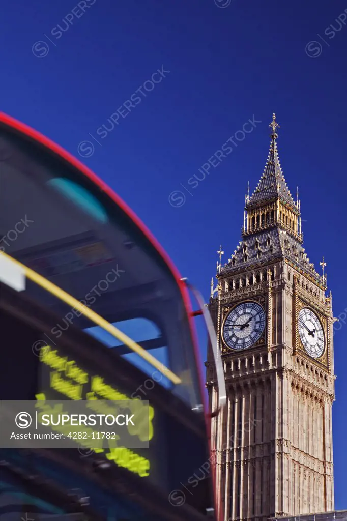 England, London, Westminster. A red double decker London bus going past Big Ben.